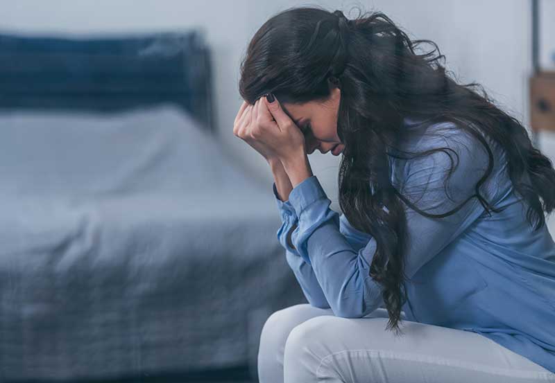 woman-in-blue-shirt-sitting-on-bed-assessment-and-treatment-of-anxiety