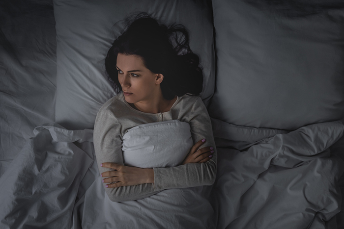 woman-with-insomnia-arms-folded-in-bed-sleep-wake-disorders